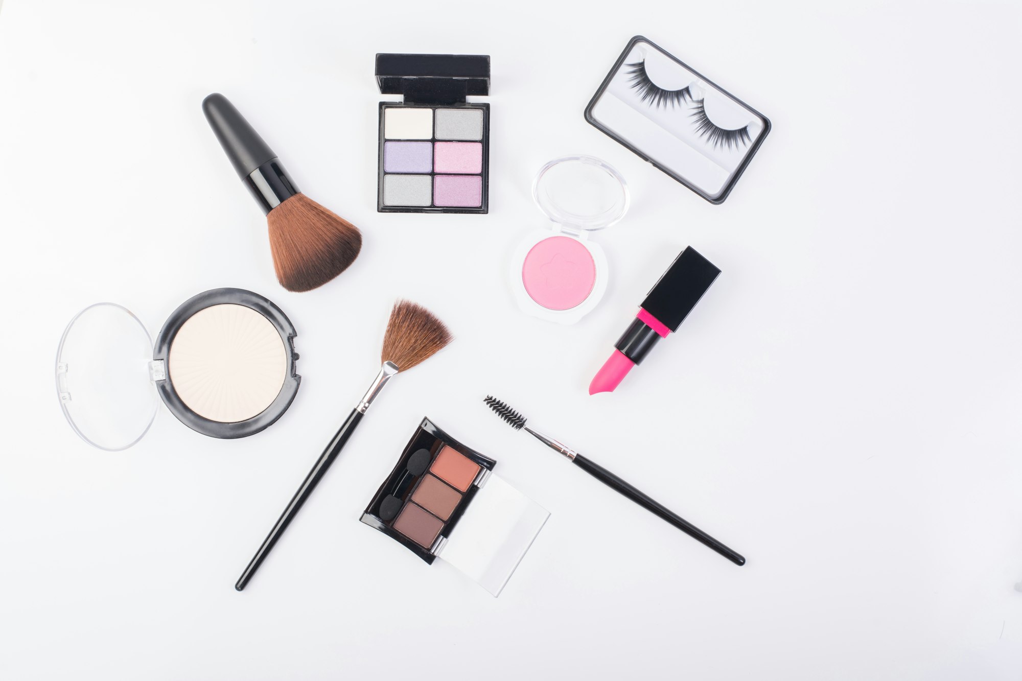 Top view of A collection of cosmetic beauty products arranged around a blank on white background.